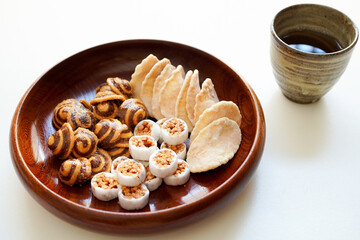 木のお皿に入ったかりんとう、生姜煎餅などの和菓子(お茶菓子) と日本茶