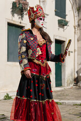Venice, Italy - People dressed in carnival masks are photographed by tourists in the scenery of the ancient Venetian palaces