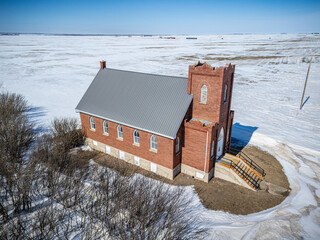 Small red brick church sits in a snowy field