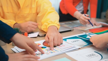 A dynamic team engages in a creative brainstorming session, collaborating on design concepts and analyzing colorful charts and drafts on a modern workspace. SACTR