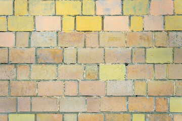 Obraz premium A wall made of yellow and pink bricks. The bricks are stacked in a pattern.