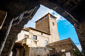 Stone arch framing a medieval tower and ancient buildings in Viterbos historic center, highlighting the citys rich architectural heritage and captivating atmosphere