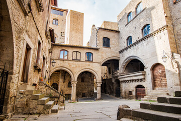 Stone buildings with arches and columns create a picturesque scene in Piazza Cappella, located in the heart of Viterbo, Italy, showcasing the city's rich history and architectural heritage