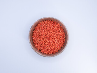 Red lentil grains, in a wooden bowl, top view, white background