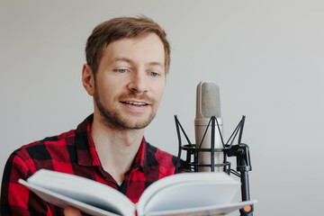 Close up of young man narrator recording audiobook using microphone at recording studio.