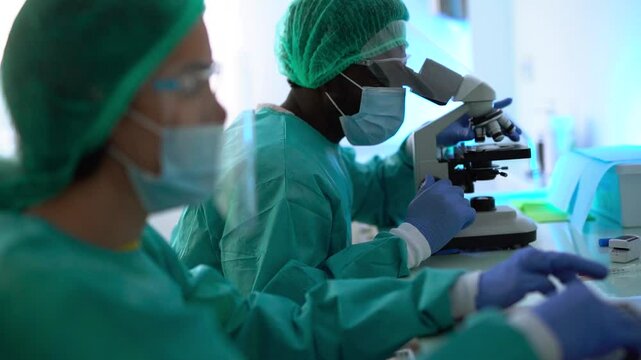 Multiracial scentist working with computer laptop and micoroscope inside laboratory hospital - Virologist concept