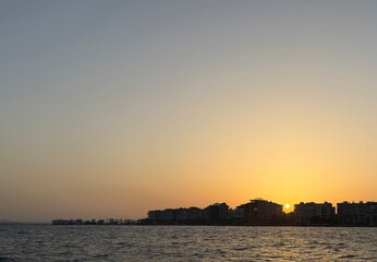 The city plunges into twilight. The sun sets between houses. Atmosphere of approaching night