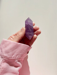 In the hand of the magician,  healer, medium holds a purple quartz crystal. An esoteric photo