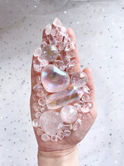 Hand of a human medium, healer, magician holds a crystal heart and other crystals of various shapes in the palm of his hand