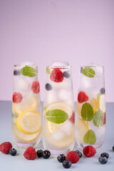 refreshing and vibrant beverages with lemon slices, mint, and berries in tall glasses on a pastel backdrop creating a crisp and inviting atmosphere, calm, peaceful, airy, zesty, chilled, quenching