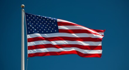Obraz premium American Flag Waving in Blue Sky - A vibrant American flag billows proudly against a clear blue sky. Perfect for patriotic themes