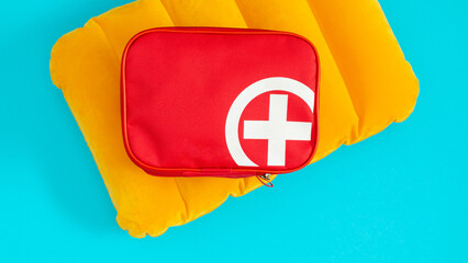 Summer sea vacation. A bright image of a red first aid kit with a white cross and an inflatable cushion for swimming on the water on a blue background.