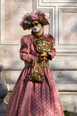 Venice, Italy - People dressed in carnival masks are photographed by tourists in the scenery of the ancient Venetian palaces