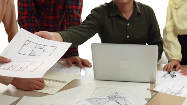Smart architect and safety engineer discussion about building plan on table with architectural document, measurement tools and wooden block scatter around at modern office. Closeup. Delineation.
