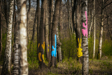 Bright, stylized bunny figures in blue, pink, and white are attached to tree trunks along a winding...
