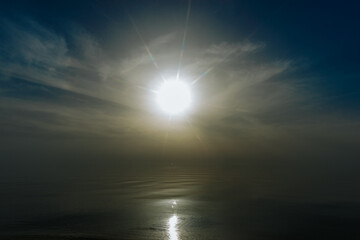 Tranquil sunset over a smooth beach shoreline with gentle waves and golden reflections on wet sand. Warm light fills the sky and water, creating a peaceful mood.