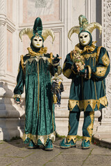 Venice, Italy - People dressed in carnival masks are photographed by tourists in the scenery of the ancient Venetian palaces