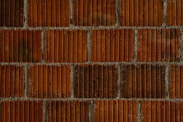 A flat brick wall with reddish tones, vertical textures, and gray mortar between them. A...