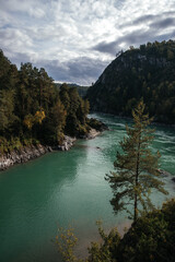 Fototapeta premium Majestic river flowing through a lush forest landscape with a small speedboat cutting across the water. Surrounded by towering cliffs and trees, creating a serene escape.