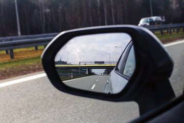 Highway in car mirror. Rearview road reflection. Fast travel concept. Modern asphalt route. Vehicle...