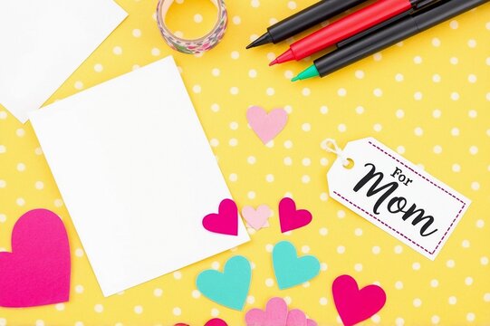 a mom tag, a blank card, pens and colorful paper flowers on a yellow polka dot background