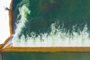 Body of water with a large wave crashing into a wall