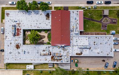 White building with a red roof and a green tree in front of it