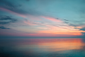 Peaceful sunset over calm ocean, pastel pink and blue hues reflecting on water, evokes serenity and tranquility, ideal for relaxation themed designs