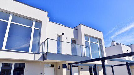 Terraced family homes in newly developed housing estate. The real estate market in the suburbs. New single family houses in a new development area. Residential homes with modern facade. 