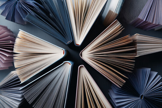 Overhead view of open books arranged in a circular pattern, showcasing cream, beige, and blue pages, creating a radial design symbolizing knowledge, learning, and literature