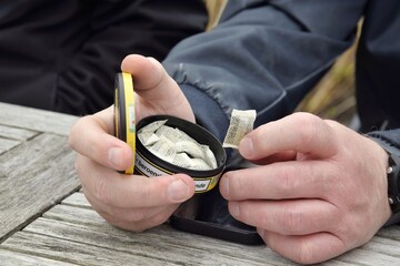 A box of snus pads in a man's hand. Swedish nicotine pouch.
