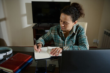 Focused Woman Writing Notes While Working from Home,