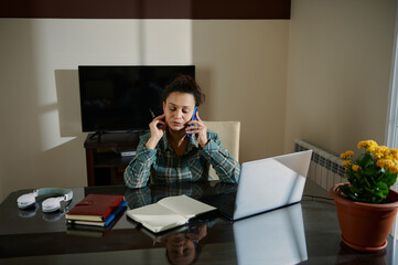 Woman Multitasking with Laptop and Phone in Home Office Environment