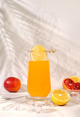 Orange juice and oranges on elegant kitchen table with long hard shadows. Modern still life with...