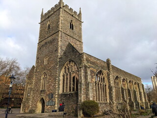 Ruins of St Peter's Church with intricate gothic architecture stands under a cloudy sky