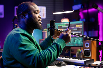 Artist songwriter performing his new musical creation in home studio, recording a new song for the...