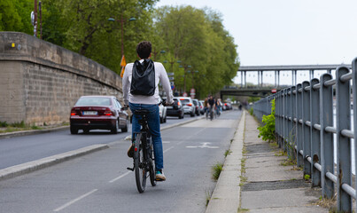 Un jeune homme avec un casque, sur son vélo sur une piste cyclable à Paris.