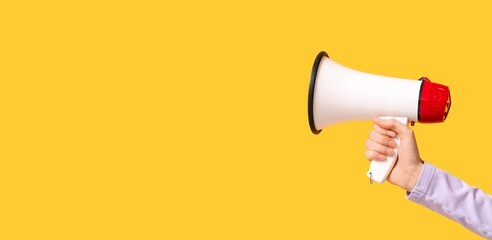 Hand holding megaphone on yellow background with space for text