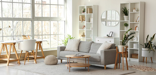Interior of light living room with grey sofa, workplace and mirror