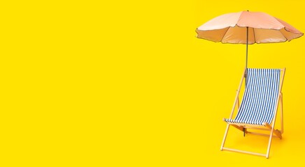 Deck chair and beach umbrella on yellow background with space for text. Summer vacation