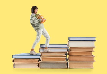 Shocked young woman with many books on yellow background