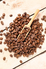 Obraz premium Scoop and coffee beans on light wooden background