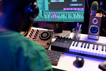 Sound engineer mixing and mastering new music on console and daw software in home studio, twisting...
