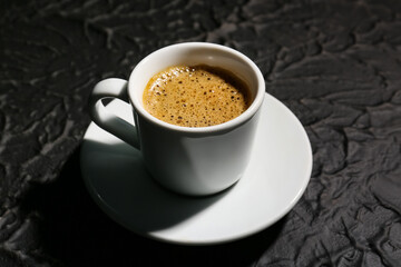 Cup of hot espresso on black background