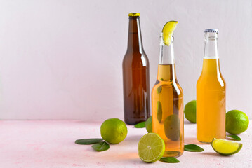 Bottles of cold beer with lime on light background