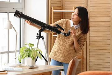 Young Asian woman using telescope at home