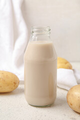 Bottle of tasty potato milk on light background