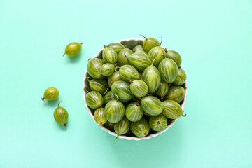 Bowl with fresh green gooseberry on turquoise background