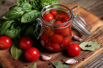 Jar with canned tomatoes and basil on wooden background
