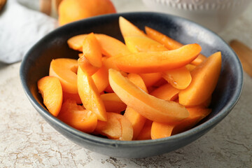 Bowl with pieces of sweet apricots on white table